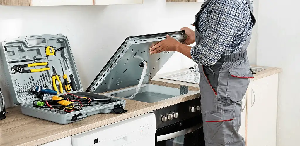 Handyman repairing a cooktop and checking wiring connections in Fort Wayne, IN