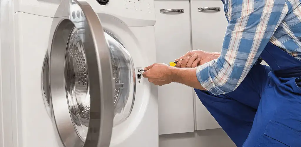 Handyman repairing a clothes dryer and checking electrical connections in Fort Wayne, IN
