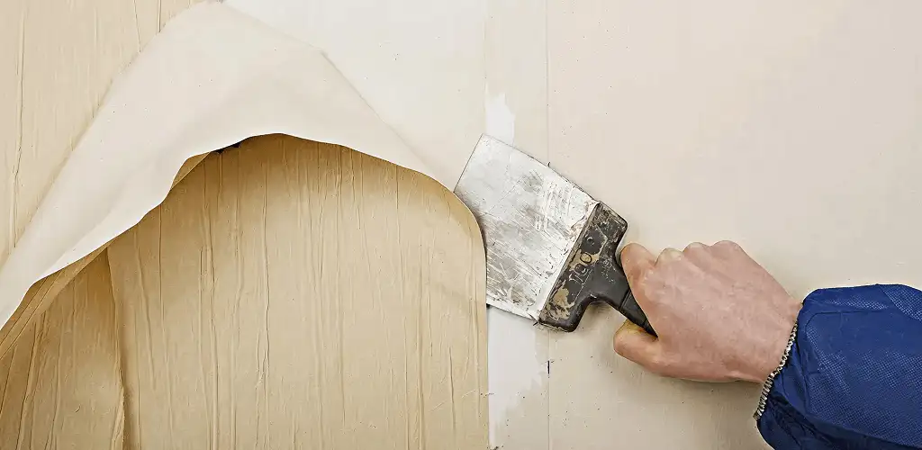 Handyman removing wallpaper with a scraper for wall preparation in Fort Wayne, IN