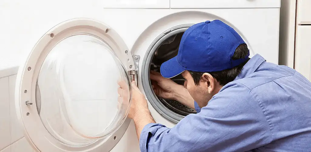 Washing machine repair handyman inspecting a front-load washer drum in Fort Wayne, IN