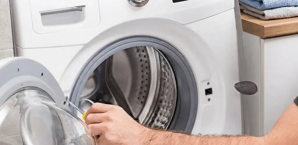 Handyman repairing a front-load washing machine and inspecting the drum in Fort Wayne, IN