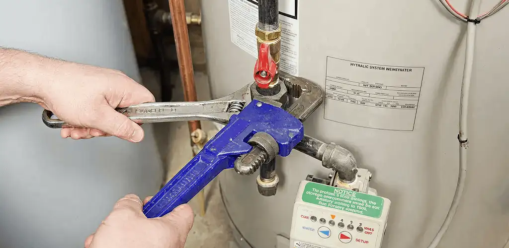 Water heater repair technician tightening the shutoff valve and supply line in Fort Wayne, IN